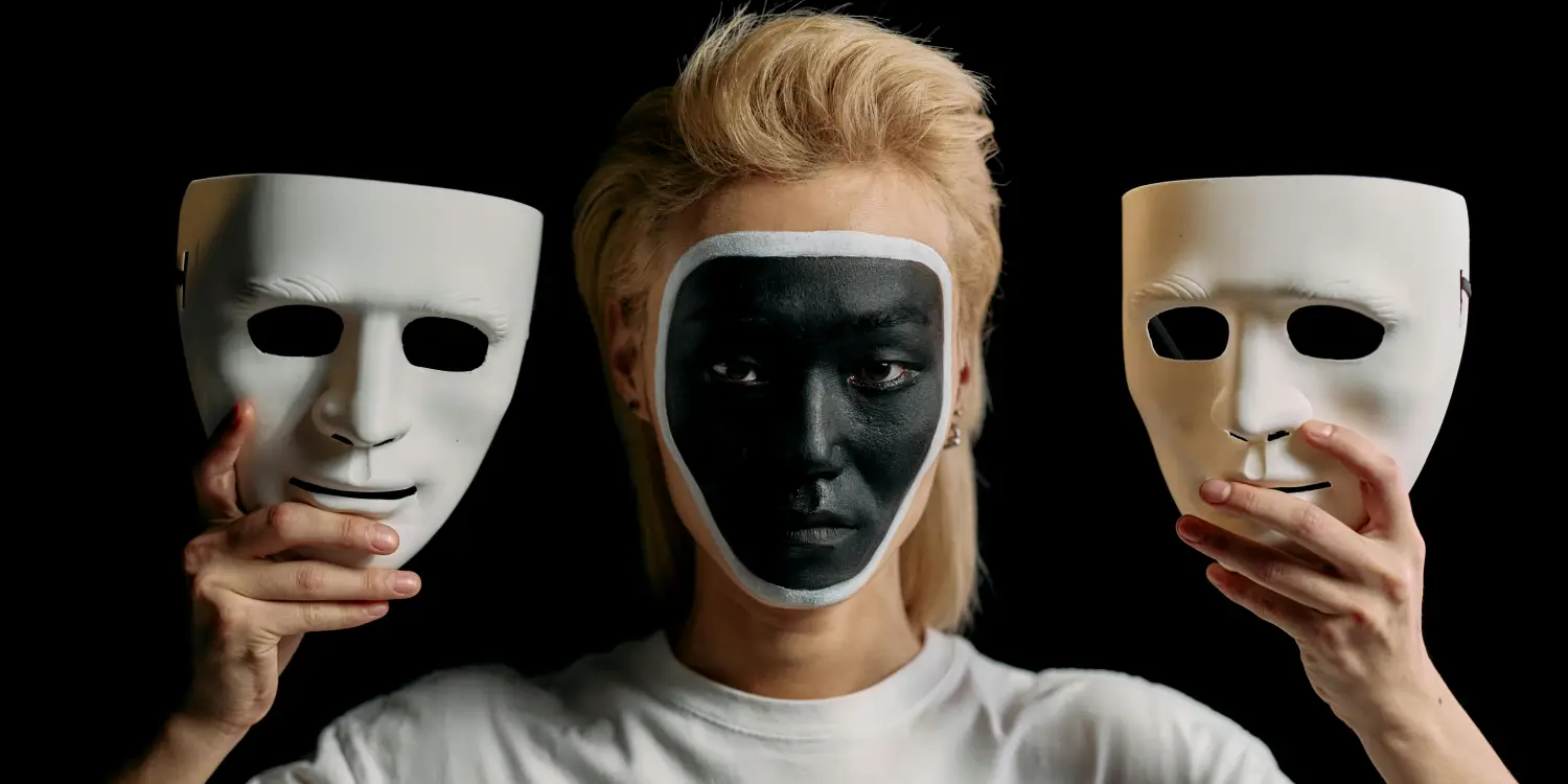 Elinde iki maske tutan yüzü siyah boyalı erkek