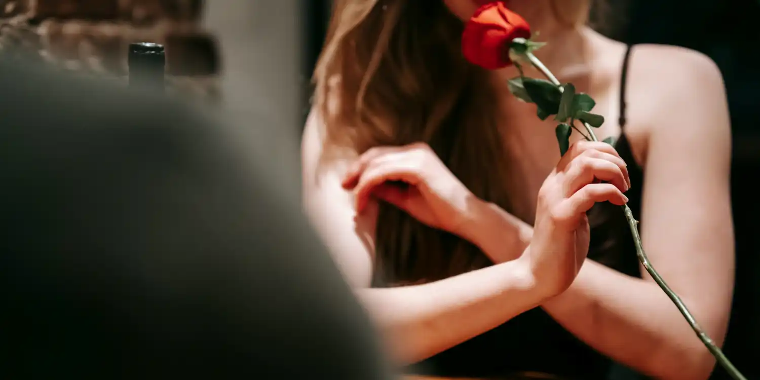 Romantik yemekte elinde gül tutan kadın